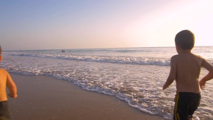 Slow motion - Two little brothers running, playing and enjoying while the camera chase them smiling and laughing