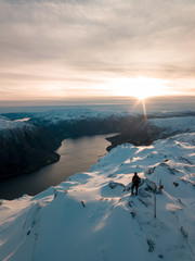 Aerial view of a snowboarder on top of the mountain. Snowboarder on the summit. Mountain landscape. Snowboard. Freeride. Drone photo. Aerial landscape. Mountain backcountry. Man silhouette on top