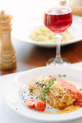 Italian food - delicious lasagne in white plate on table with red wine.