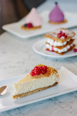 Cheesecake with red currant berries on white plate.