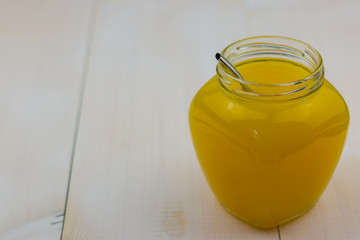 Yellow juice in glass closeup on white wood board. Fresh exotic fruit drink.