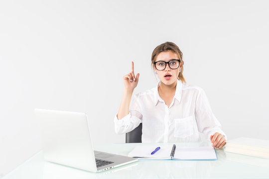 Woman having new idea pointing index finger up thinking work stand near white desk with pc laptop isolated on white background. Achievement business career concept. Copy space for advertisement