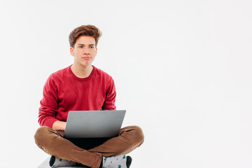 Teenager student with funny face working at laptop on white back