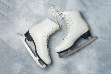 Concept winter holidays. White figure skates on grey background.