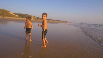 Slow motion - Two little brothers running, playing and enjoying while the camera chase them smiling and laughing