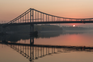 Fototapeta na wymiar Sunrise view of pedestrian Park bridge and Dnipro river in Kyiv, Ukraine