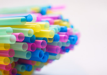 Close up on multiple plastic straws laying on a white background