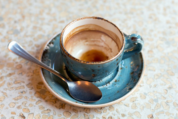 Almost empty blue modern coffee cup on granite table background.