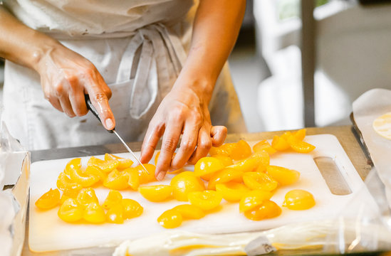 Woman cooking at the kitchen, cutting peaches with knife