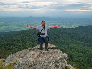 Asian Fat man stand on rocky cliff and trekking on Khao Luang mountain in Ramkhamhaeng National Park,Sukhothai province Thailand