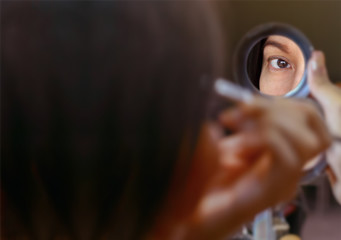 Close-up 40s Asian woman preparing makeup her beauty face and holding puff pastry. This photo easy to change picture in the circle mirror by clipping path. Beautiful blurred image and selective focus.