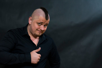 Punk in a black shirt. The finger of the hand shows upward. The look is sly and interrogative.