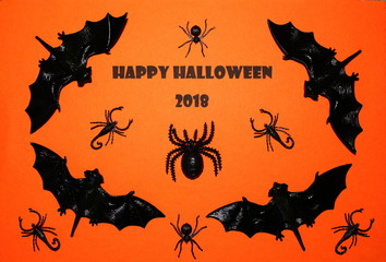 Happy Halloween 2018 text with black bats, spiders and scorpions against a bright orange background.