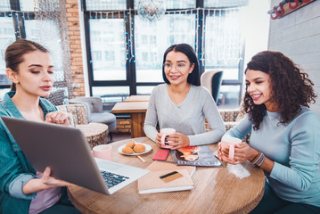 New ideas. Serious smart woman holing her laptop while explaining her ideas to the colleague