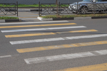 Yellow crosswalk on asphalt. Yellow painted crosswalk road line markings with moving car in background