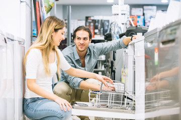 Happy couple of friends choosing appliances