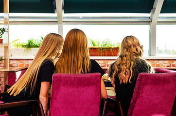 Three girls with long hair in a cafe