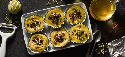banner of raw vegan cupcakes from pistachios, cashews and dates with chocolate and lime. and chamomile tea in glass cups. healthy holiday dessert. good healthy food on black background