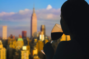Female hand with glass of wine on Manhattan background. New York city.  Service on the roof of the...