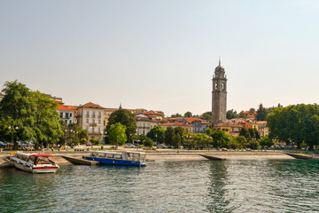 Panorama di una cittadina sul lago con barche, campanile e alberi verdi in estate, Pallanza, Lago...
