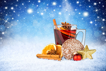 cup mug of hot mulled wine with gingerbread christmas decoration anise star cinnamon sticks xmas bauble star on winter snow blue night sky stars background