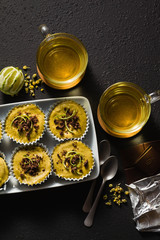 raw vegan cupcakes from pistachios, cashews and dates with chocolate and lime. and chamomile tea in glass cups. healthy holiday dessert. good healthy food on black background