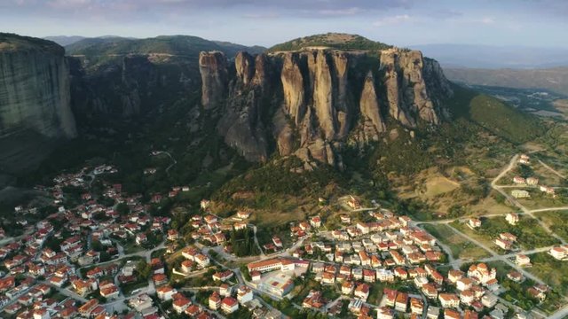 Aerial shot old European city Kalambaka in amazing natural valley at sunset pullback view of mountain Meteora great landmark of high rocks and modern village