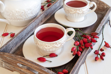 Rose hip tea in white cups with fresh rose hips