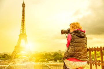 photographer on Place du Trocadero of Tour Eiffel at sunset. Traveler woman in Paris, France, Europe. Eiffel Tower on blurred background. Travel and tourism in Europe.