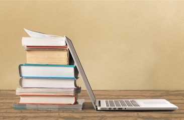Stack of books with laptop on table