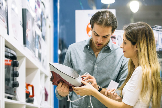 Young woman and man choosing a steam iron in an appliance store