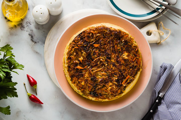 savory salty  Upside-Down pie from white cabbage, carrots and onions. gluten free no eggs , with chickpea flour. family breakfast or party snack on a white marble table