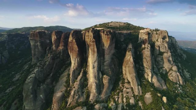 Aerial shot panoramic view amazing landscape at sunset high mountains Meteora with monasteries historical landmark near city Kalambaka beautiful blue sky panning shot