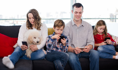 Smiling family members spending time playing with smartphones