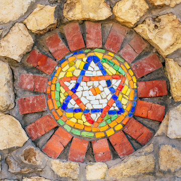 Mosaic star of David on stone wall.
