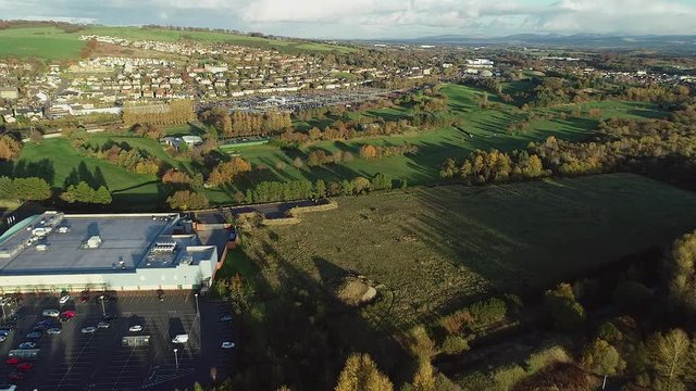 Aerial footage over the town of Bathgate in West Lothian, Scotland. Approaching the Railway station as a passenger train departs..