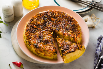 savory salty  Upside-Down pie from white cabbage, carrots and onions. gluten free no eggs , with chickpea flour. family breakfast or party snack on a white marble table