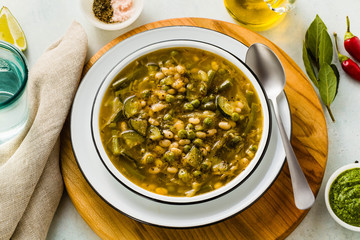 gluten free green minestrone with cannellini beans. on the table with spices and arugula pesto. Traditional Italian Tuscan soup. healthy food for the whole family on the blue table