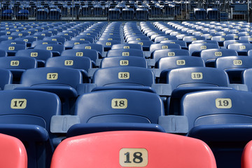  Empty rows and sections of red and blue seats in a sports stadium.