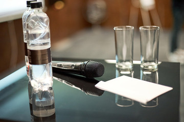 Microphones on abstract blurred of speech in seminar room or front speaking conference hall light, white chairs for people in event meeting convention hall in hotel.