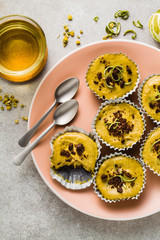 raw vegan cupcakes from pistachios, cashews and dates with chocolate and lime. and chamomile tea in glass cups. healthy holiday dessert. good healthy food on a pink plate and gray background