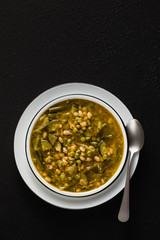 gluten free green minestrone with cannellini beans. on the table with spices and arugula pesto. Traditional Italian Tuscan soup. healthy food for the whole family on black background