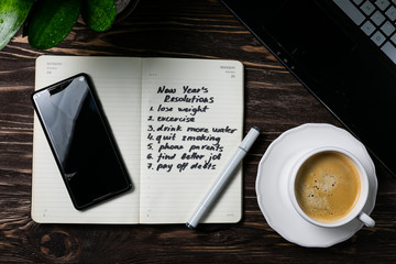 New year resolutions concept -list of resolutions in notepad, phote, coffee, notebook, top view