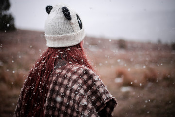 happy girl catching snowflakes in nature with panda cap