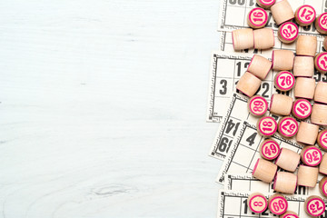 Board game lotto or bingo. Wooden lotto barrels with numbers and cards on white table with copy space. Vintage game.