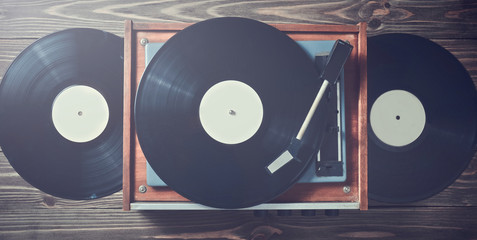 Vinyl player with plates on a wooden table. Entertainment 70s. Listen to music. Top view.