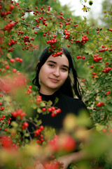 Young female picking cherries outside in the orchard.Beautiful teenager  girl make selfie on blooming spring rhododendron trees background. Mobile shot.
