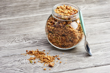 Homemade granola in a glass jar on a wooden table