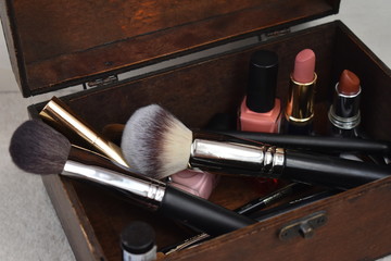 Cofre de madera con brochas de maquillaje, pintauñas, pintalabios 