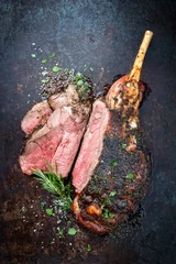 Poster Traditional barbecue leg of lamb sliced with spice and herb as top view on a metal sheet © HLPhoto